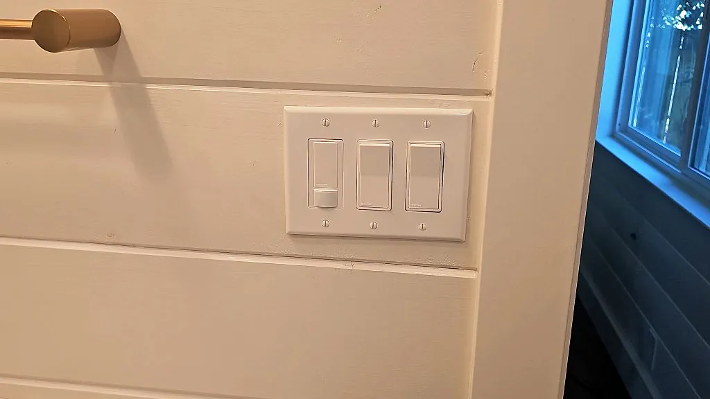 Three decorator switches under one plate on a shiplap wall