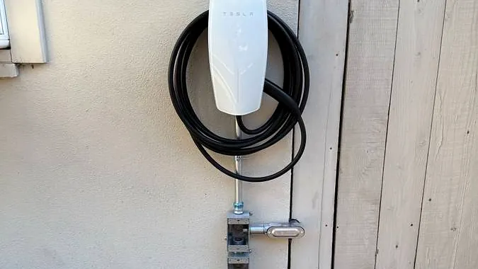 Wall-mounted EV charger beside a side gate with a disconnect below