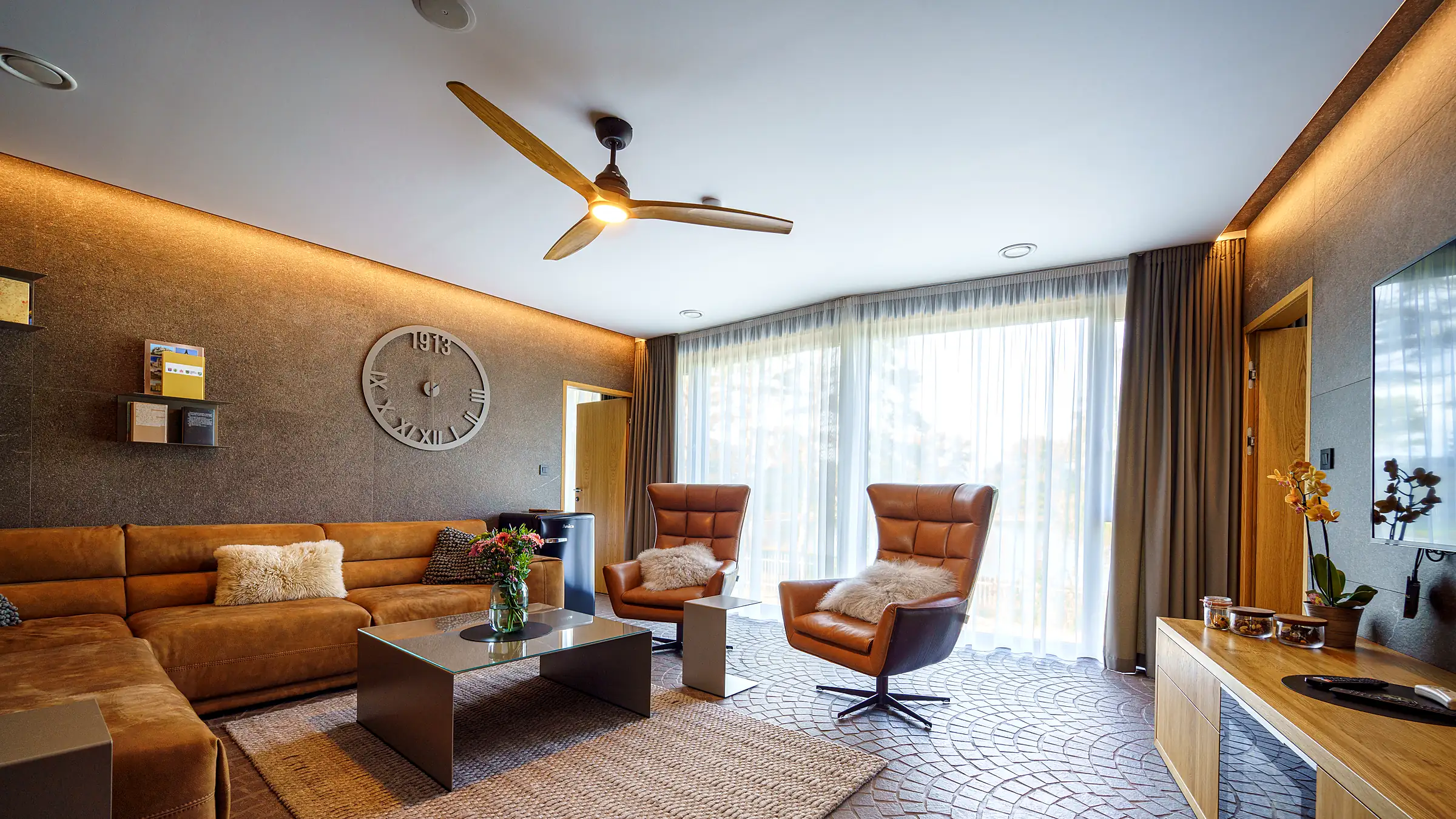 Modern living room with a wood-blade ceiling fan and warm cove lighting
