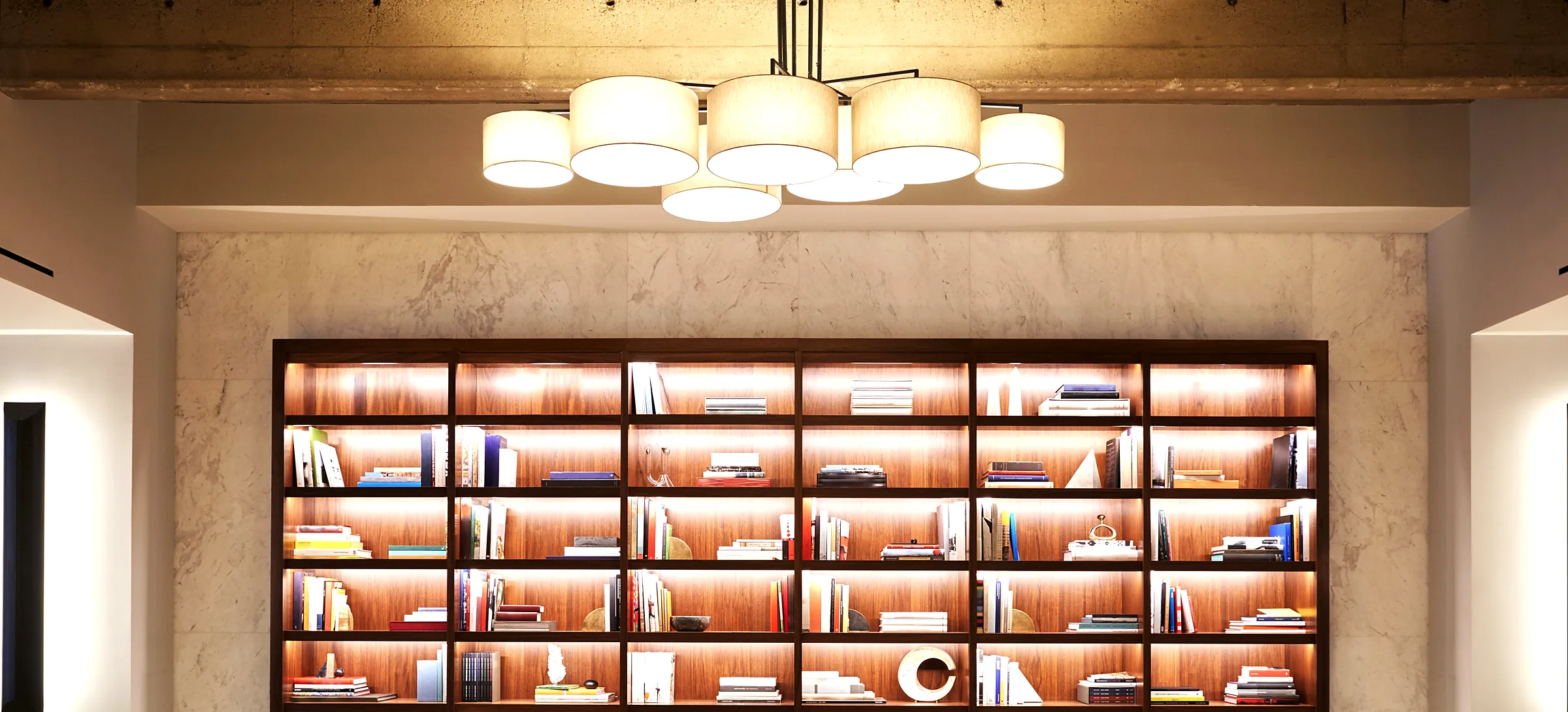 Warmly lit room with a pendant chandelier, wall sconces and illuminated shelving
